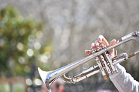 A person's hand holding a silver trumpet. Original public domain image from <a href="https://commons.wikimedia.org/wiki/File:Jazz_band_in_Nola_(Unsplash).jpg" target="_blank" rel="noopener noreferrer nofollow">Wikimedia Commons</a>