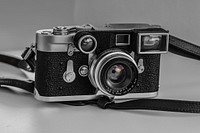 Vintage camera with leather black strap on a white surface. Original public domain image from <a href="https://commons.wikimedia.org/wiki/File:Nick_Karvounis_Photography,_K%C3%B8benhavn,_Denmark_(Unsplash_zagEcOkRFMk).jpg" target="_blank" rel="noopener noreferrer nofollow">Wikimedia Commons</a>