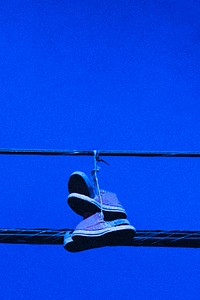 Sneakers hanging from power lines, neon blue summer aesthetic