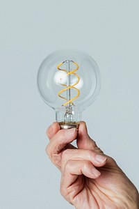 Senior man holding a light bulb against a blue background