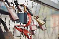Padlocks on a fence, accompanied by a red ribbon.. Original public domain image from Wikimedia Commons