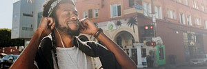 Black man enjoying music while walking in downtown