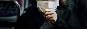 Sick woman in a mask coughing in public during coronavirus pandemic