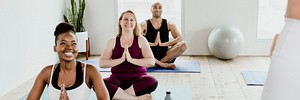 Cheerful people doing a Sukhasana pose in a studio