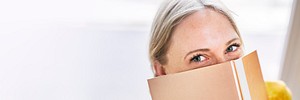 Woman hiding behind a shiny gold notebook