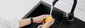 Woman rinsing a yellow lemon in a sink