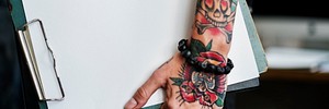 Tattooed hand holding a blank paper clipboard website banner template