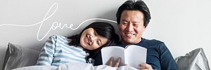 Cheerful couple reading a book together in bed