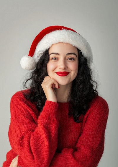 Woman wearing Christmas-themed and a Santa hat sweater happy expression.