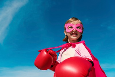 Superhero girl smiling on blue sky for education portrait