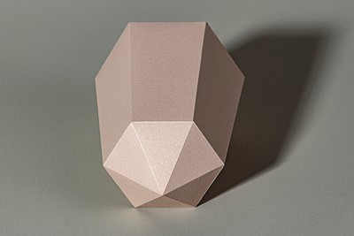 Pink hexagonal prism paper craft on a gray background