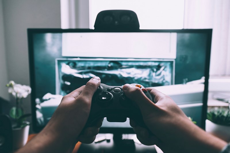 Close up of gamer holding controller and playing video games on computer.  Woman using joystick to play online digital games in front of monitor.  Person with modern gaming equipment Stock Photo 