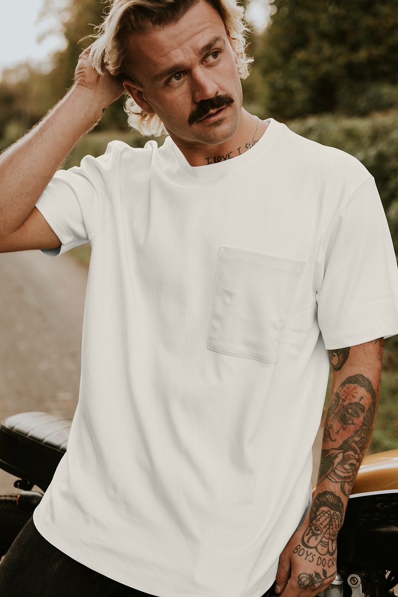 Premium Photo  A young bearded man in a white shirt and tattoos stands on  a black wall