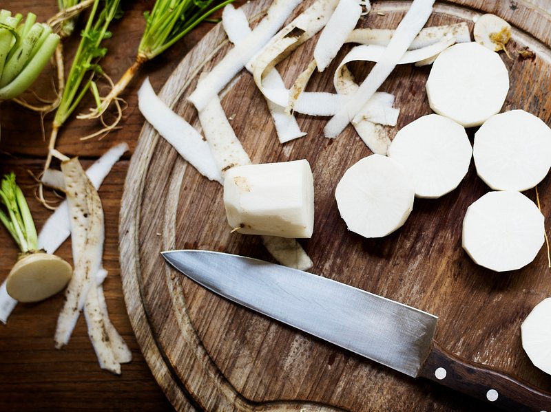 Fresh chopped radishes and a knife on a cutting board on a wooden