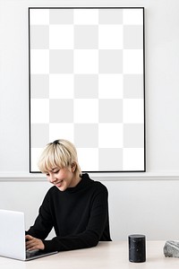 Woman working on her laptop with a blank frame hanging on a wall