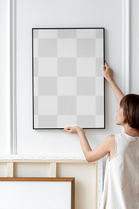 Woman arranging frame mockup png on a wall in a Japandi decor room