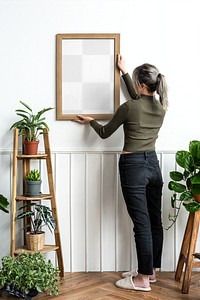 Transparent png frame being hung on the wall by a young woman 