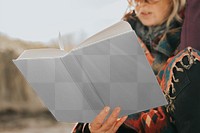 Book png mockup held by a retired senior by the beach