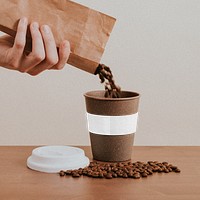 Hand pouring coffee beans into a cork coffee cup design element