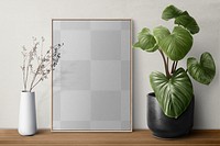 Picture frame png mockup on a shelf with plants against a wall