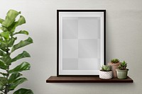 Dark picture frame png mockup on a shelf against a wall