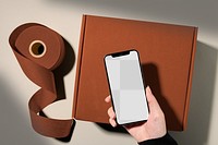 Phone png mockup, transparent screen, online business concept, brown parcel box below