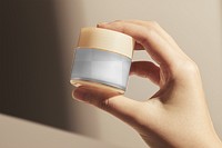 Cosmetic jar png mockup transparent, held by hand in natural light