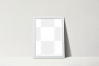 White picture frame leaning against on a beige wall