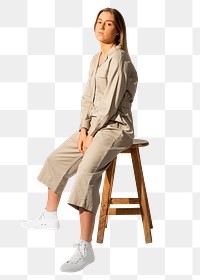 Woman png mockup in beige jumpsuit sitting on chair on transparent background