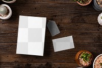 Png business card mockup on wooden table with plants flat lay