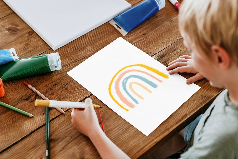 Editable paper mockup on a table, being drawn by a kid