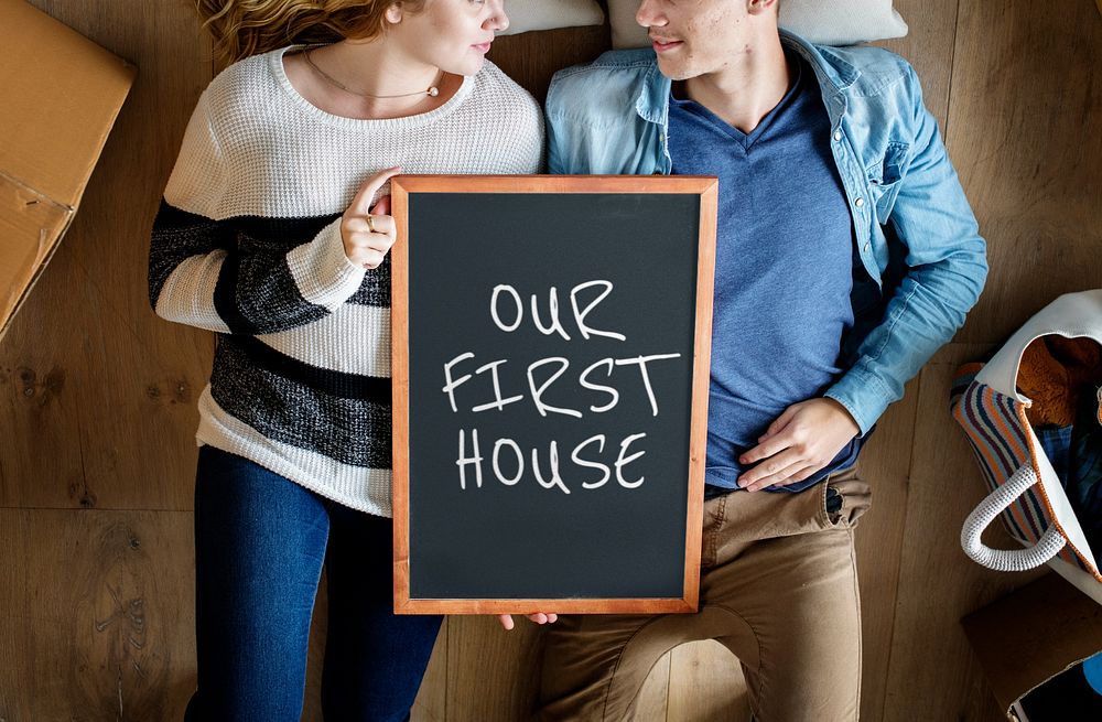 Editable sign mockup with a couple holding it together, our first home 