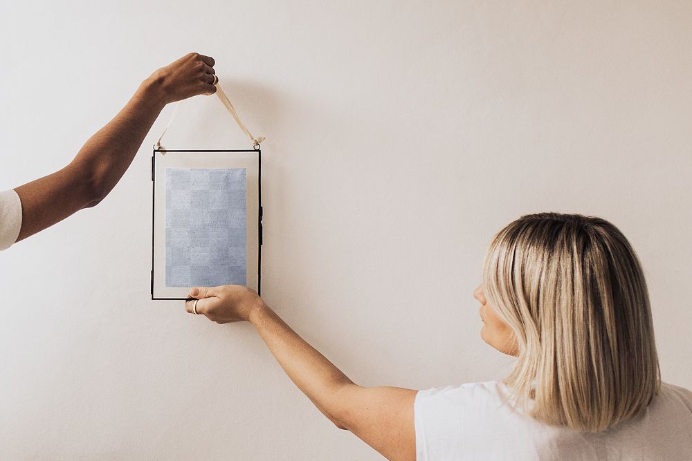 Women hanging png frame mockup on white wall