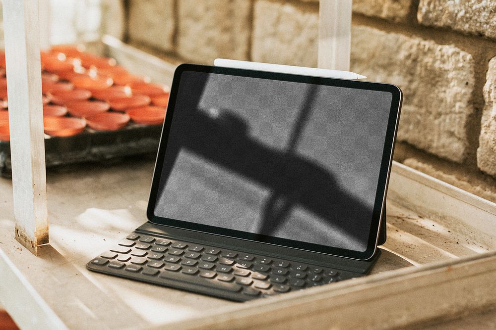 Png black tablet screen mockup with keyboard on a gardening wooden table