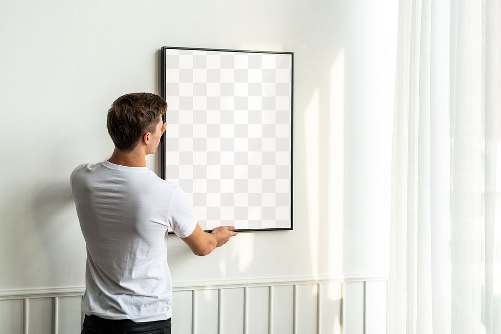 Transparent png frame being hung by a young man on a white minimal wall