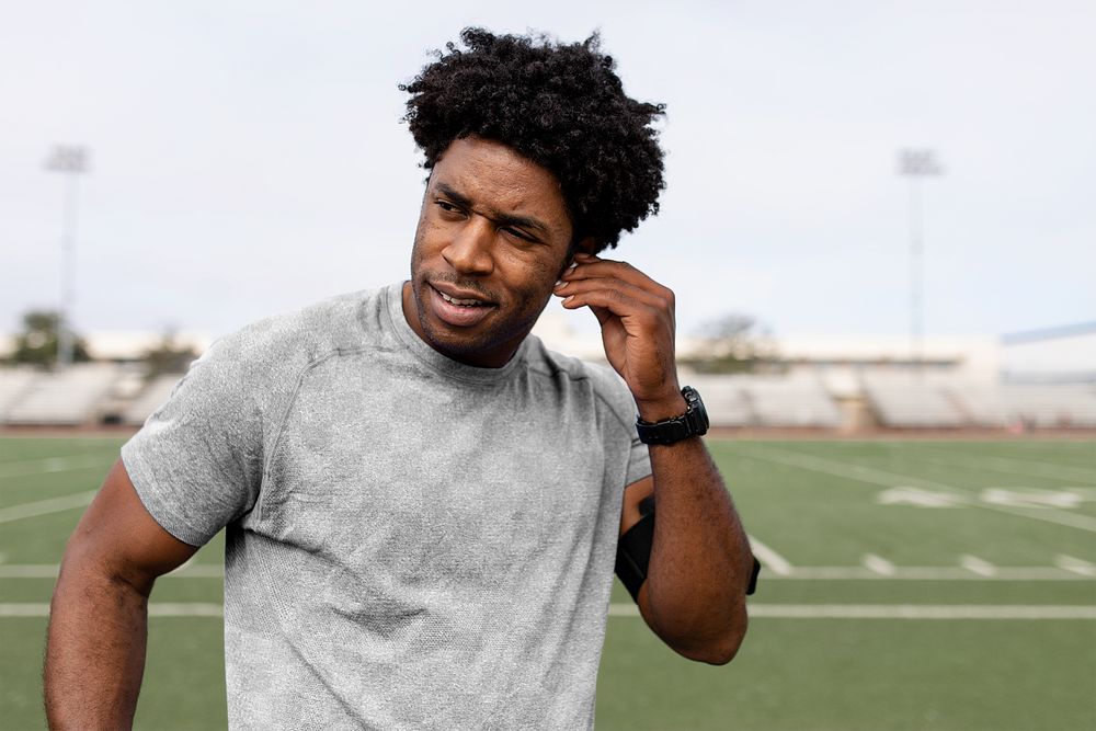 Sports top mockup png on athlete putting the earbud on his ears