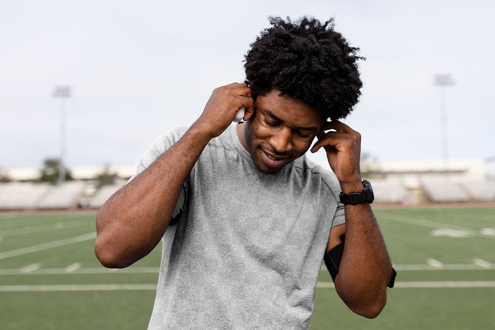 Sports top mockup png on athlete putting the earbud on his ears