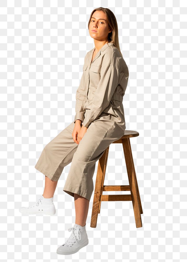Woman png mockup in beige jumpsuit sitting on chair on transparent background