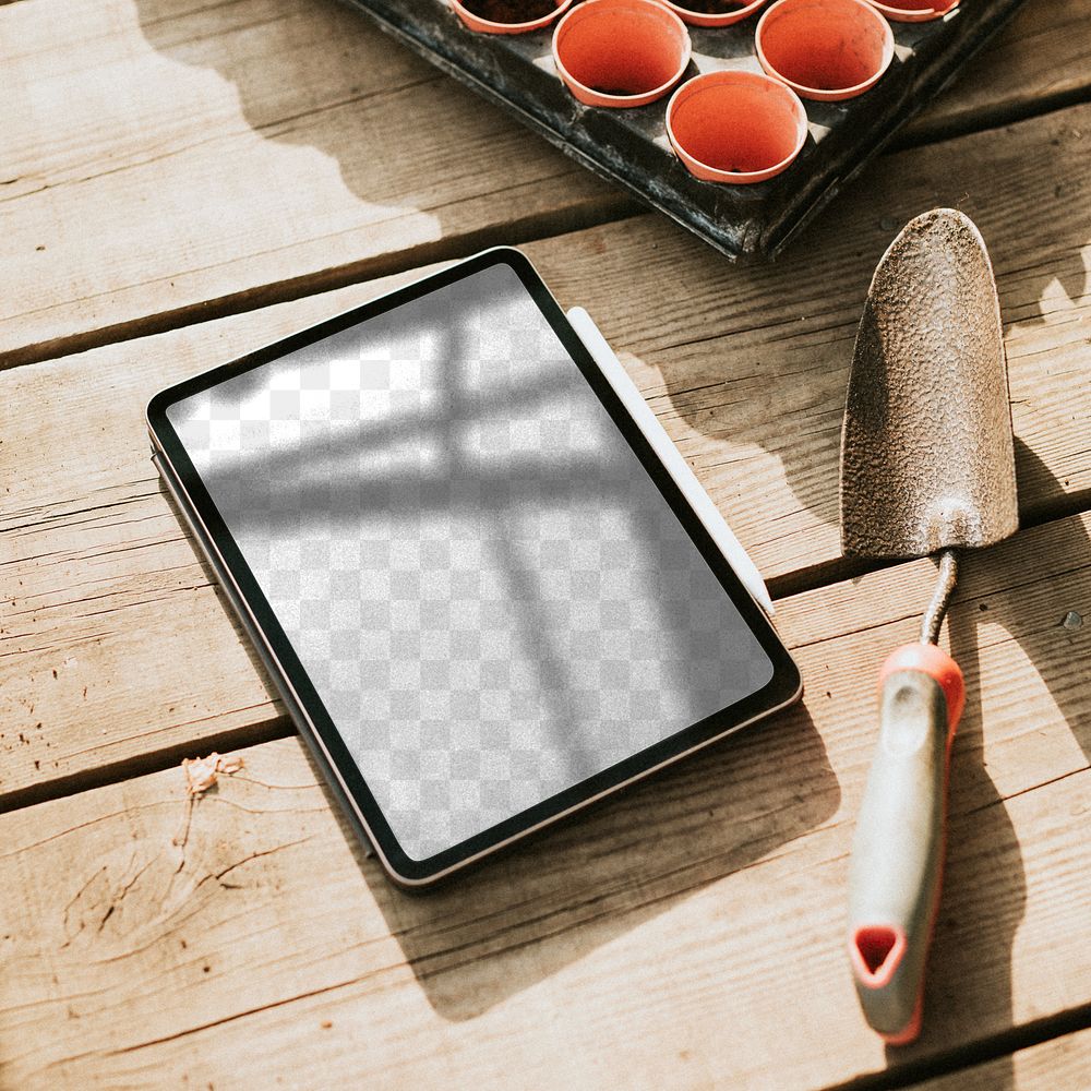 Png tablet screen mockup by a gardening trowel on a wooden table