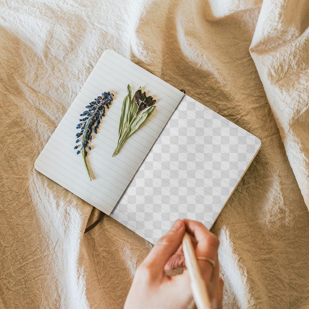 Open notebook png mockup with flowers on linen blanket