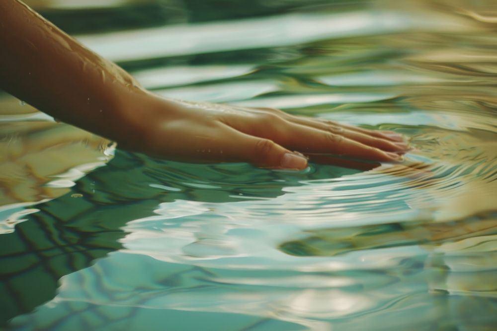 Hand touching water surface pool outdoors nature.