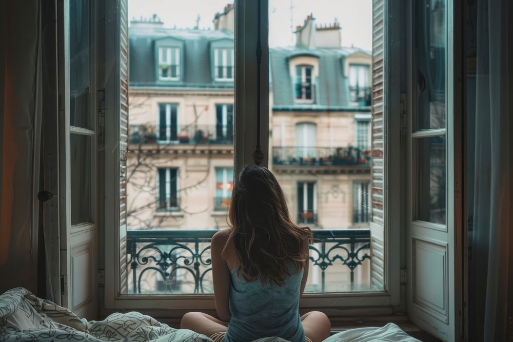 Woman sitting in front of the window building architecture windowsill.