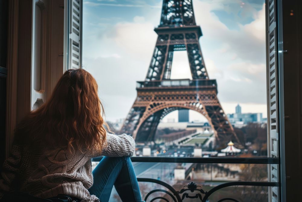 Woman sitting in front of the window tower architecture eiffel tower.