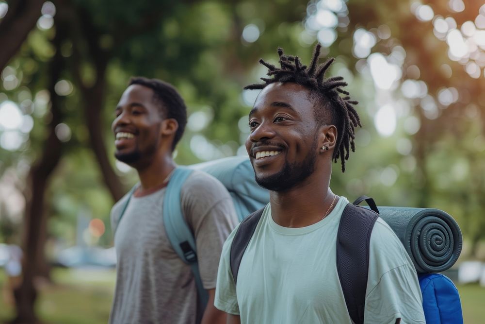 A black Cheerful man with exercise mat walking by male friend in park laughing person human.