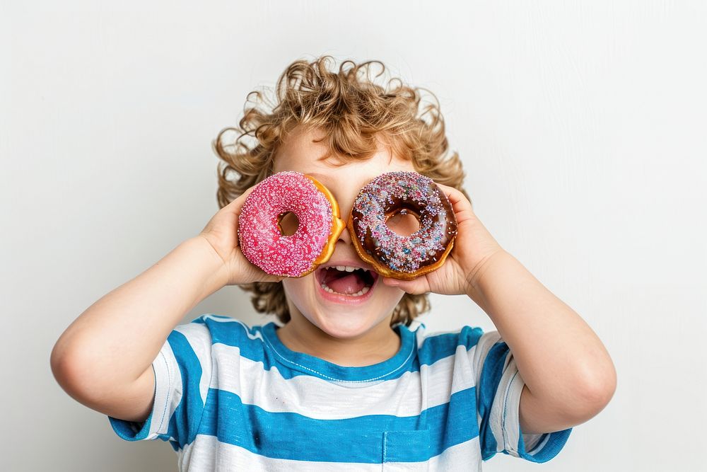Child holds donuts as two eyes food person human.
