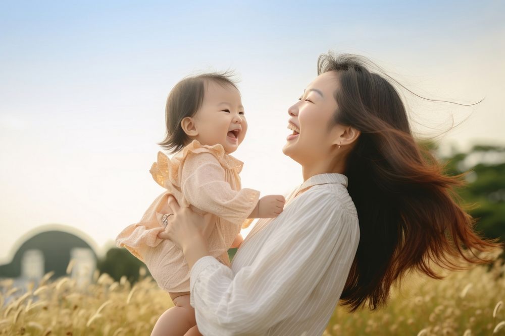 Happy Asian mother plays with daughter laughing happy baby.
