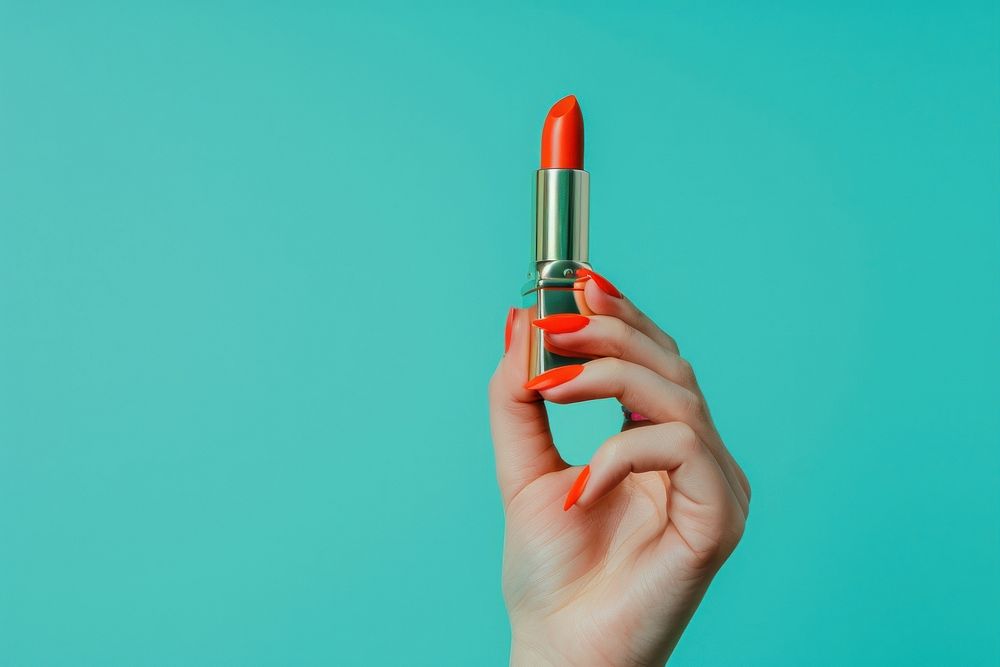 Vertical photo shot of a hand holding a orange lipstick cosmetics.