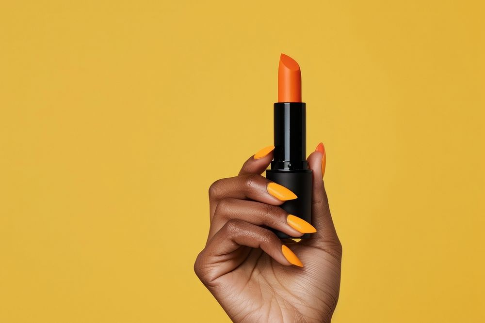 Vertical photo shot of a hand holding a orange lipstick cosmetics nail polish.
