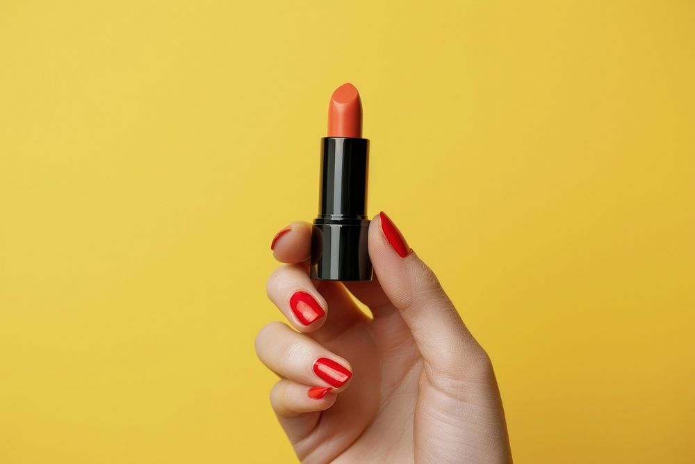 Vertical photo shot of a hand holding a pecch color lipstick cosmetics nail polish.