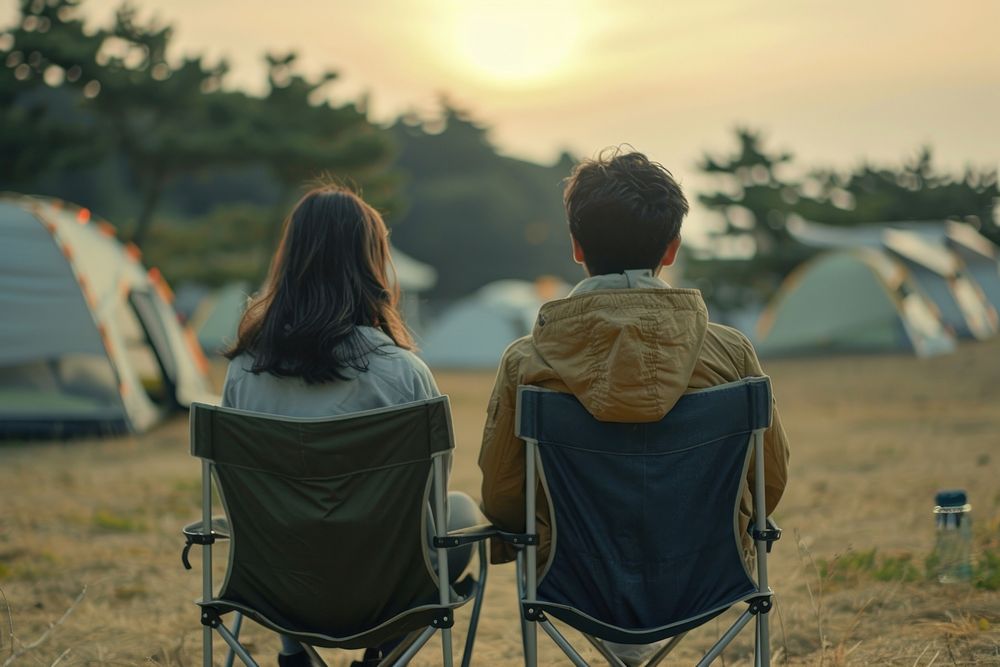 The back of couple sitting on empty white folding chair camping while seeing outdoor concert outdoors nature architecture.